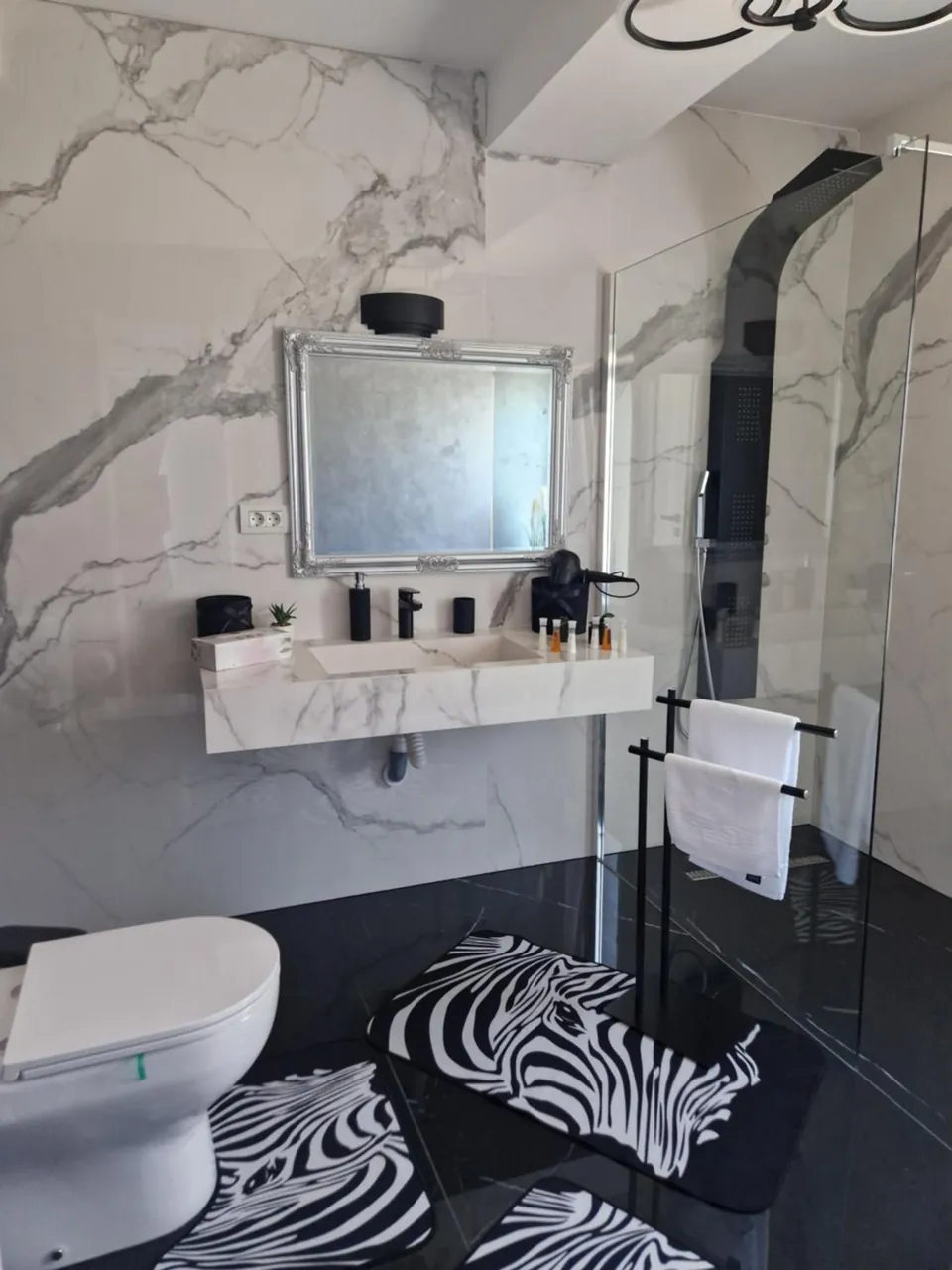 Baie cu marmură, duș și covoraș cu model zebră