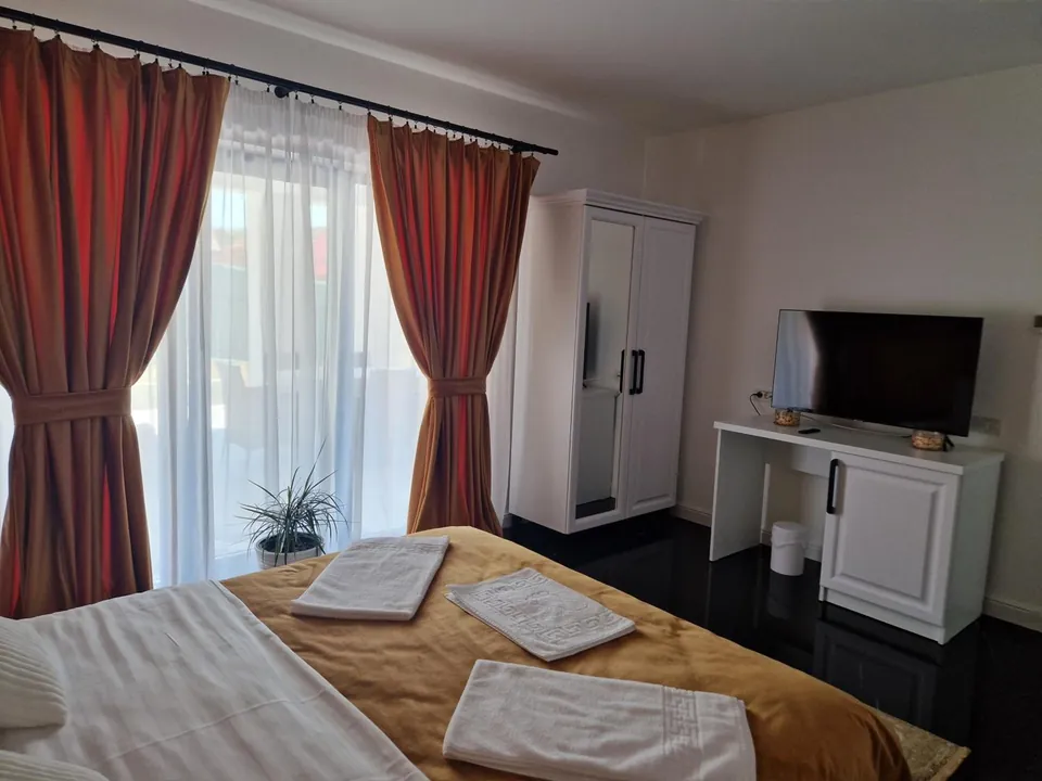 Cameră dublă cu draperii cărămizii și TV cu ecran plat