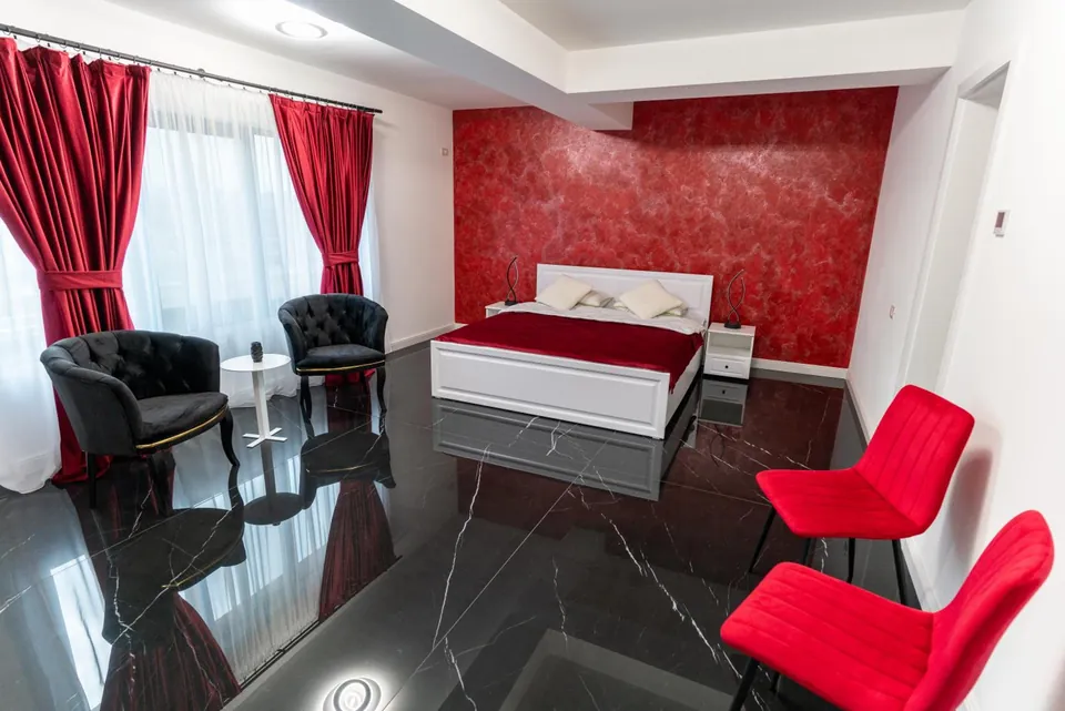 Cameră dublă spațioasă cu draperii roșii și fotolii