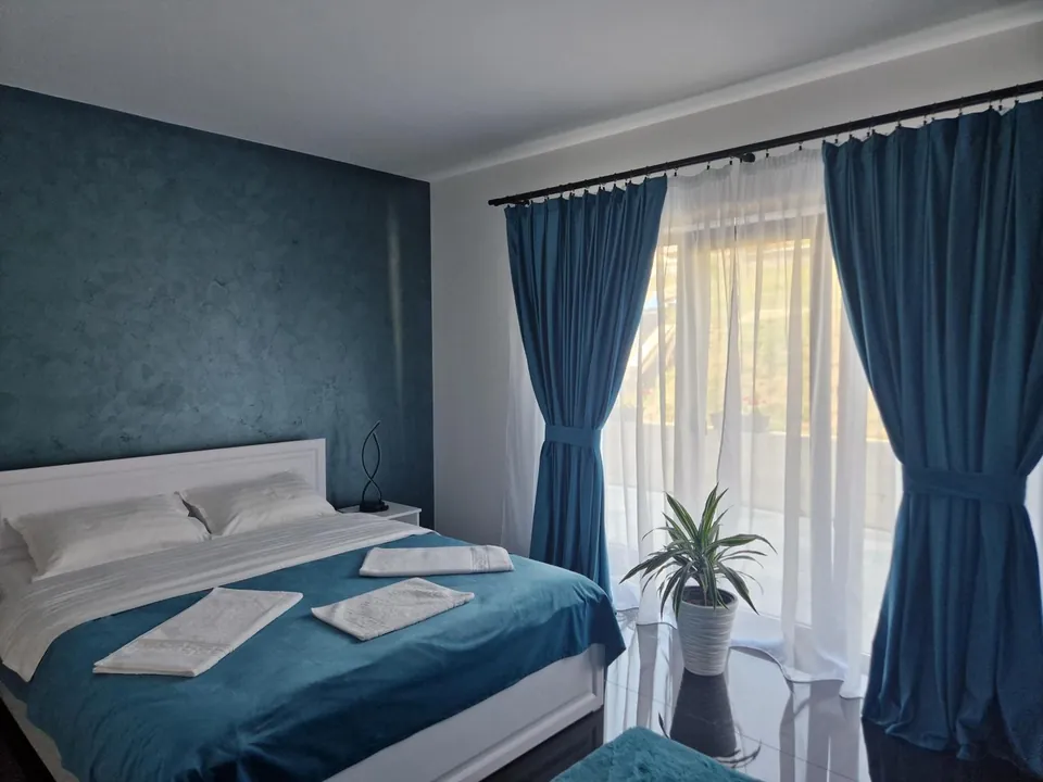 Pat dublu cu cuvertură turcoaz și draperii lungi