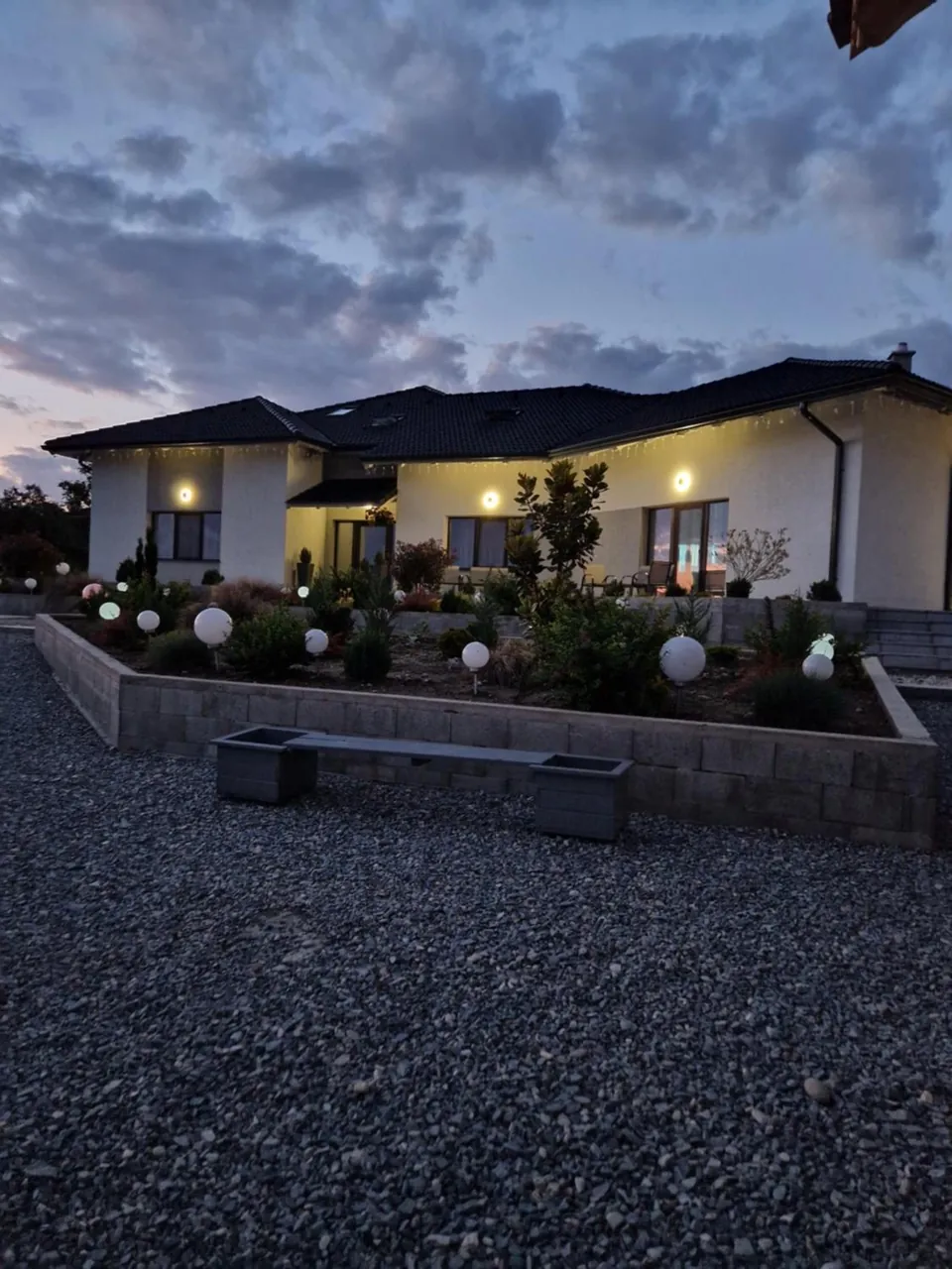 Curtea cu pietriș și grădina luminată seara la DAR House