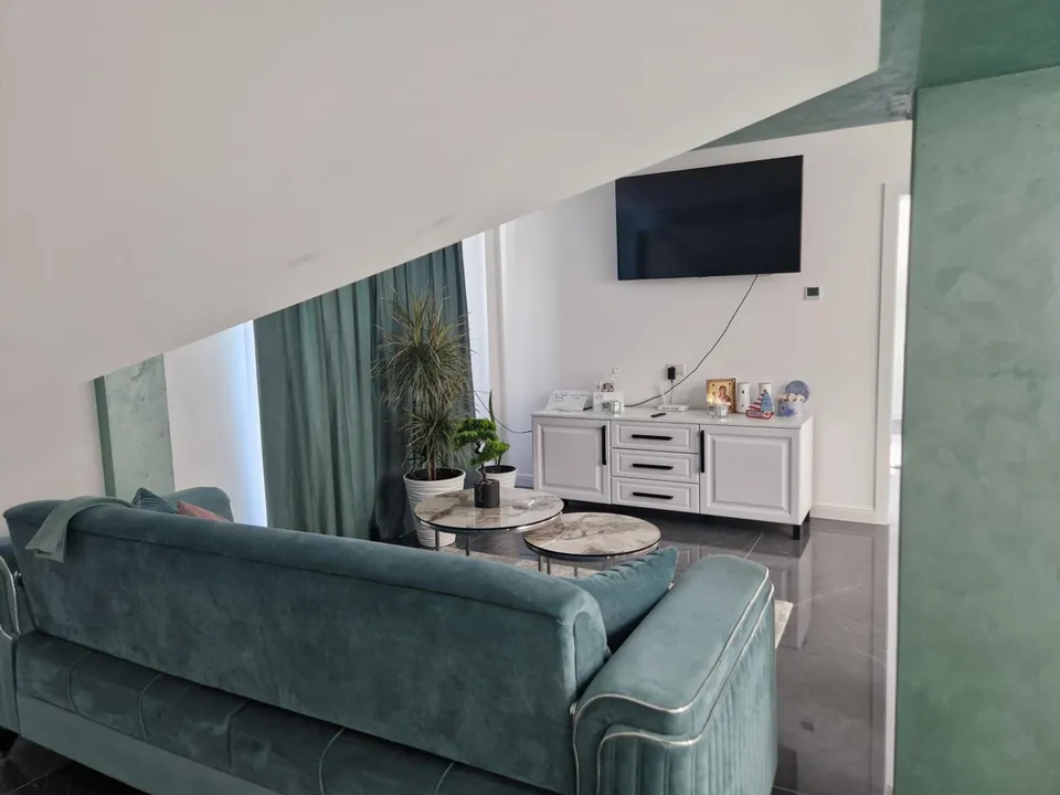 Living verde cu canapea și TV cu ecran plat